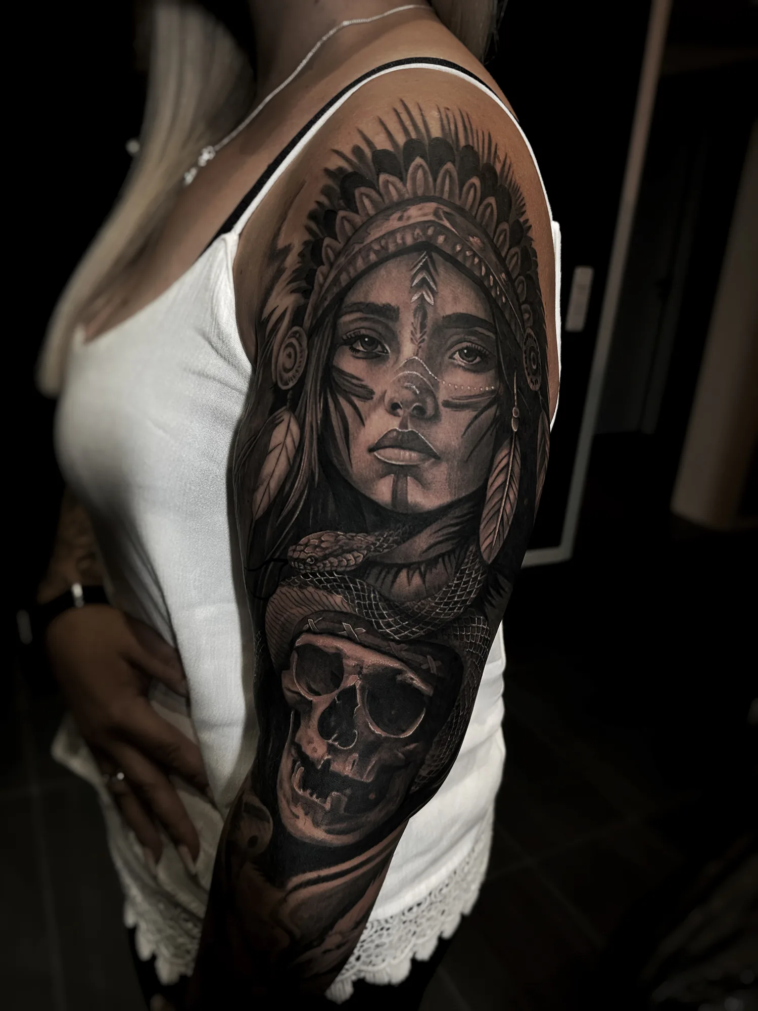 Oberarm-Tattoo: Frau mit Federschmuck, Schlange und Totenkopf
