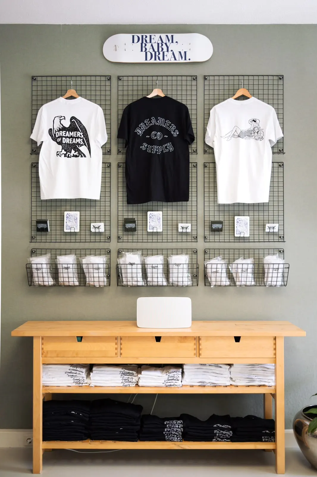 Merch-Wand mit T-Shirts unter dem Schriftzug „Dream, Baby, Dream“